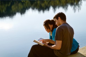 Couple Reading The Bible By A Lake